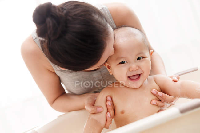 Jovem mãe beijando e banho adorável criança infantil feliz — Fotografia de Stock