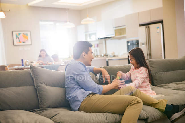 Щасливий батько з чарівна маленька дочка сидить і граючи разом на дивані — стокове фото