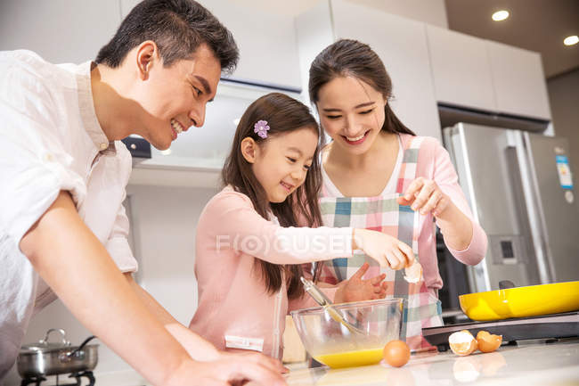 Счастливая китайская семья с одним ребенком приготовления пищи вместе на кухне — стоковое фото