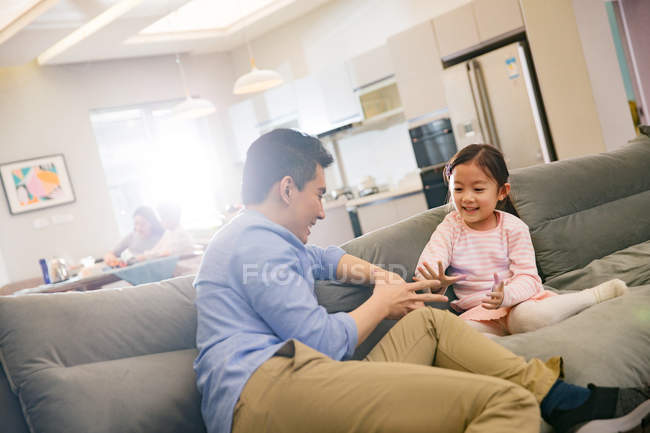 Щасливий батько з чарівною маленькою дочкою сидить і грає разом на дивані — стокове фото