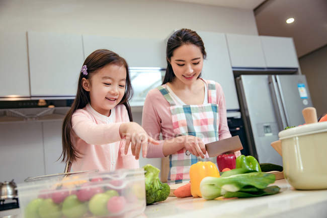 Glücklich junge asiatische Mutter und entzückende kleine Tochter Kochen zusammen in Küche — Stockfoto