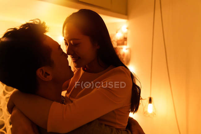 Lado vista de feliz joven asiático pareja abrazos y besos en la noche - foto de stock
