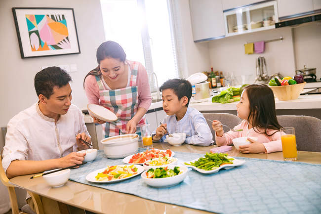Felice famiglia asiatica con due bambini che cenano insieme a casa — Foto stock