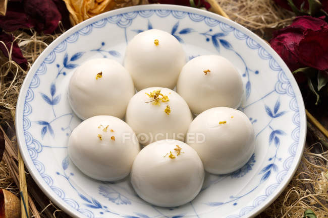 Close-up view of glutinous rice balls on plate and dry flowers — Stock Photo