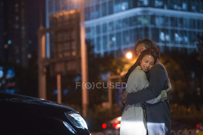 Feliz asiático pareja abrazando en calle en la noche - foto de stock