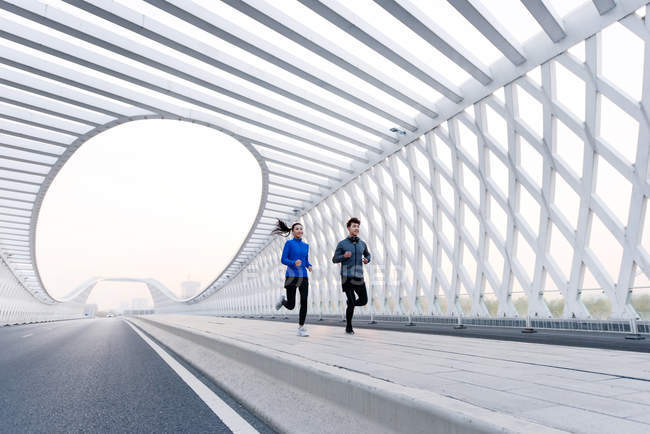 Ganzkörperansicht junger Jogger beim gemeinsamen Sportkleidungstraining in der Brücke — Stockfoto