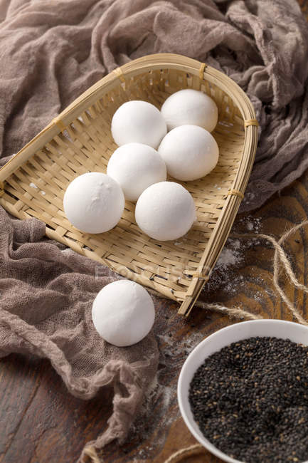 Glutinous rice balls in wicker container and sesame seeds on table — Stock Photo