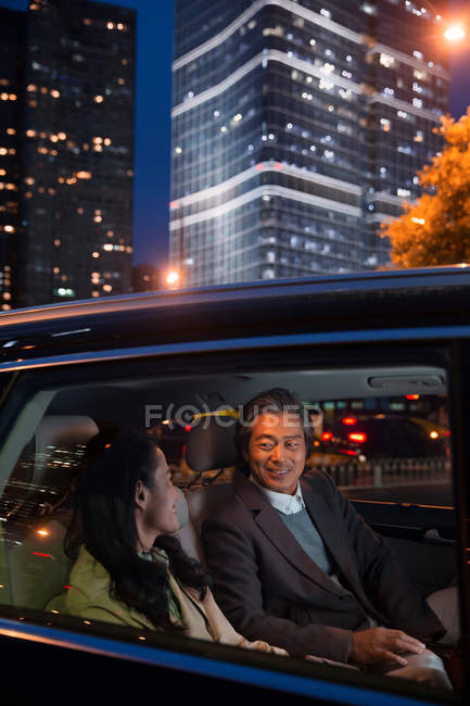 Щаслива азіатська пара їде в машині і дивиться один на одного ввечері — стокове фото