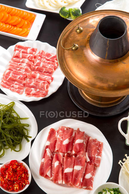 Високий кут зору мідного гарячого горщика, м'яса та овочів на столі, концепція чашки — стокове фото