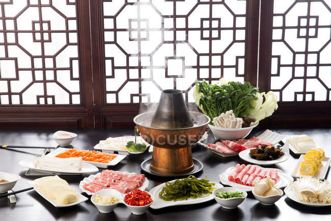 High angle view of various ingredients on plates, chopsticks and copper hot pot, chafing dish concept — Stock Photo