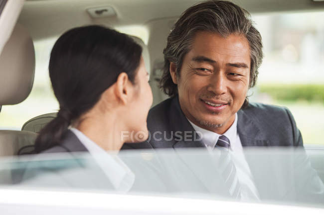 Усміхнені азіатські ділові люди сидять в машині — стокове фото