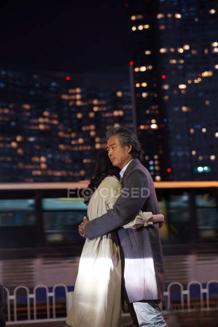 Щаслива азіатська пара обіймає на вулиці ввечері — стокове фото