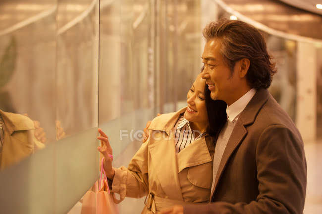 Affectionate asian couple shopping in mall and looking at showcase — Stock Photo