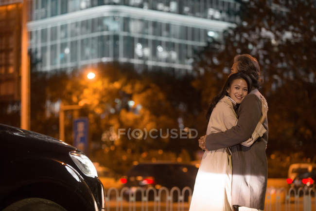 Happy asian couple hugging on street at evening — Stock Photo