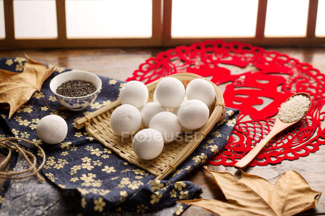 Klebrige Reisbällchen im Weidengefäß und Sesam auf dem Tisch — Stockfoto