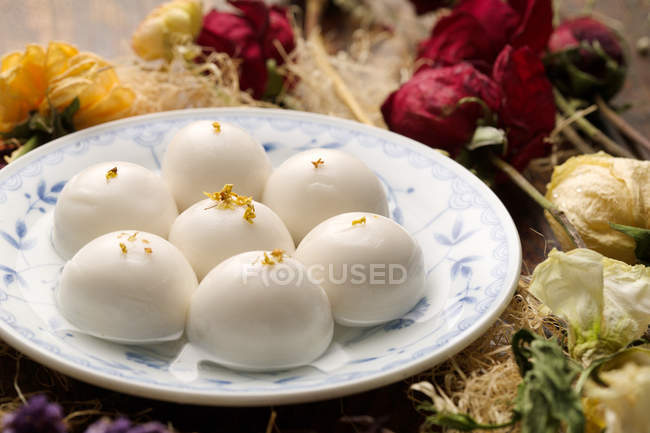 Nahaufnahme von süßen klebrigen Reisbällchen auf Teller und trockenen Blumen — Stockfoto