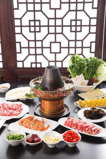 High angle view of various ingredients on plates and copper hot pot, chafing dish concept — Stock Photo