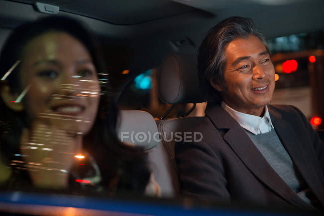 Happy asian couple riding in car at evening — Stock Photo