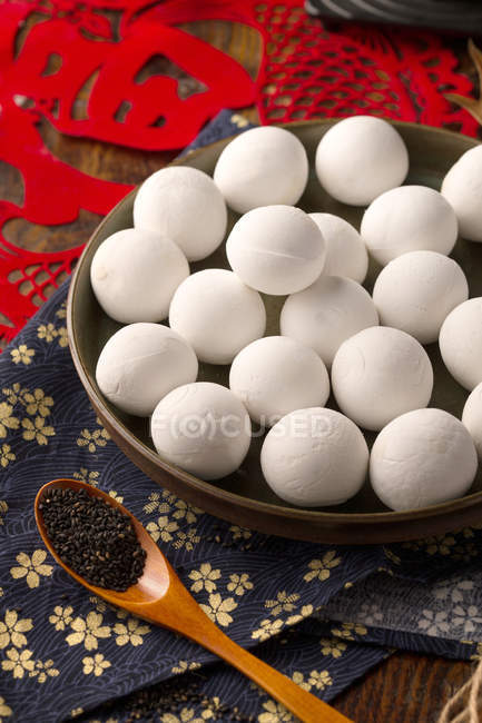 Glutinous rice balls on plate and wooden spoon with sesame seeds on table — Stock Photo