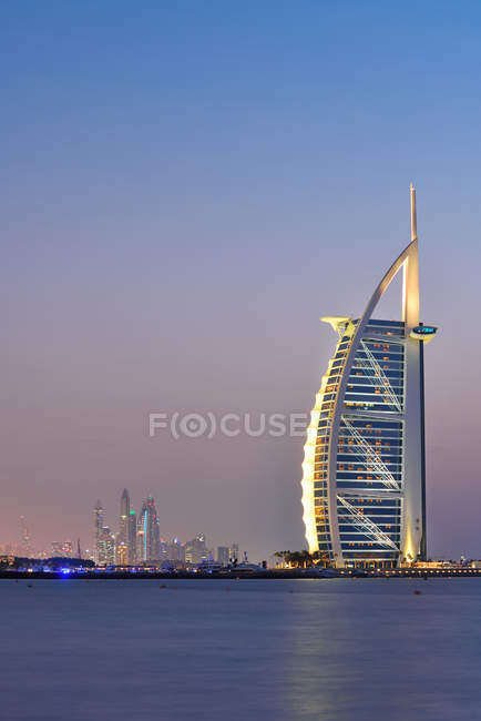 Dubái, Emiratos Árabes Unidos - 10 de octubre de 2016: El iluminado hotel y puerto deportivo Burj Al Arab al atardecer, vista desde la playa de Jumeirah, mirando al suroeste . - foto de stock