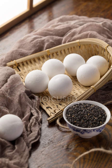 Palline di riso glutinose in contenitore di vimini e semi di sesamo sul tavolo — Foto stock