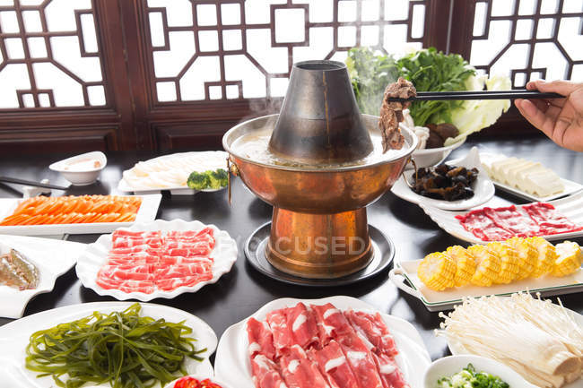 Wow Walter Cunningham Condition Partial view of person holding chopsticks with meat above copper hot pot,  chafing dish concept — chinese food, close up - Stock Photo | #266530178
