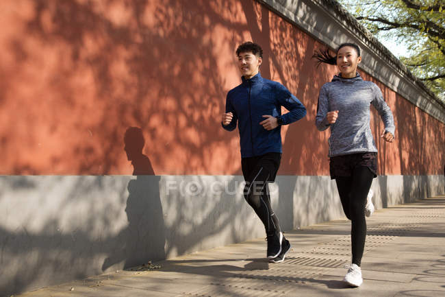 Повний вигляд спортивної молодої пари, що біжить разом на вулиці — стокове фото