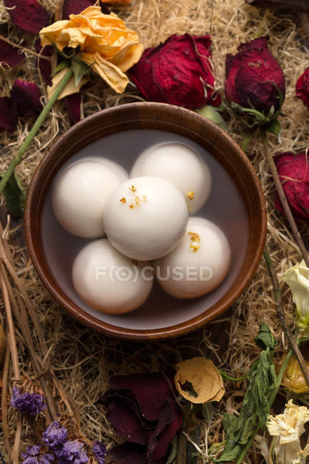 Вид сверху на клейкие рисовые шарики в миске и сухие цветы — стоковое фото