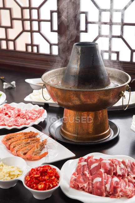 Медная горячая кастрюля, мясо и морепродукты на столе, тертое блюдо концепции — стоковое фото