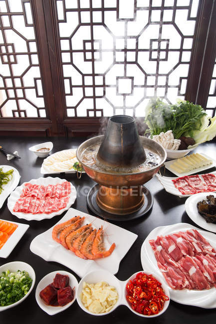Vue grand angle des assiettes avec divers ingrédients, baguettes et chaudron en cuivre, concept de plat à frotter — Photo de stock