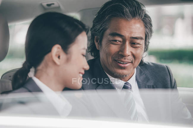 Улыбающиеся азиатские бизнесмены, сидящие в машине — стоковое фото