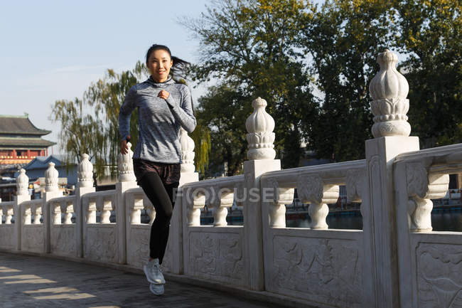 Volle Länge Ansicht der schönen lächelnden asiatischen Mädchen in Sportbekleidung läuft im Freien — Stockfoto