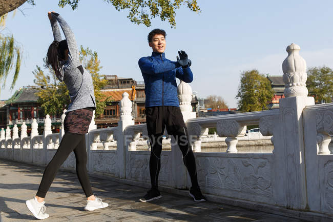 Молодая азиатская пара растягивается на улице перед тренировкой — стоковое фото