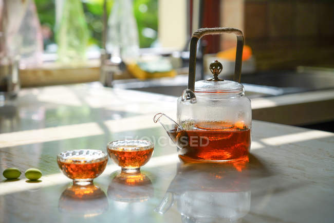 Close-up view of glass tea set with kettle and glass cups on table — Stock Photo