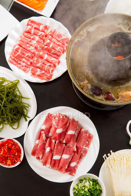 Vue du dessus de la viande et des légumes sur des assiettes et un chaudron en cuivre, concept de plat à frotter — Photo de stock