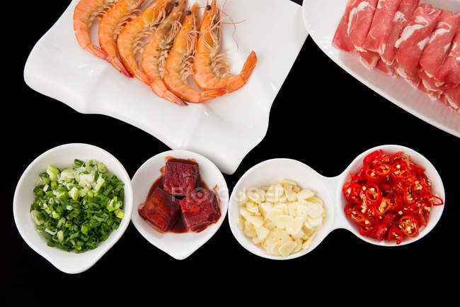 Close-up view of delicious hot pot dishes on white plates on black surface — Stock Photo