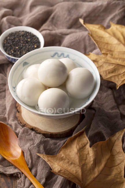 Vista close-up de tigela com bolas de arroz glutinoso e sementes de gergelim na mesa — Fotografia de Stock