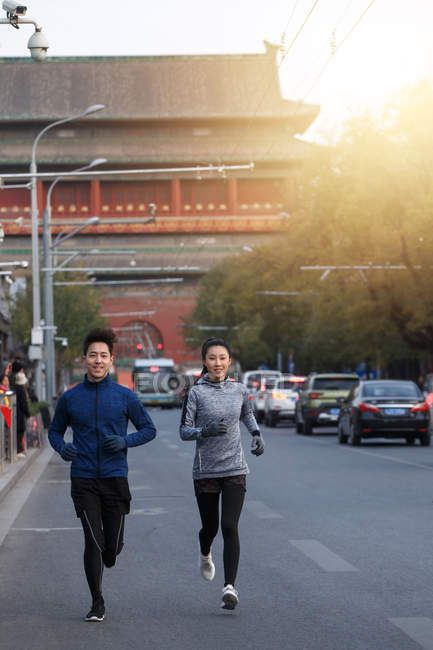 Sorridentes jovens atletas masculinos e femininos correndo juntos na rua — Fotografia de Stock