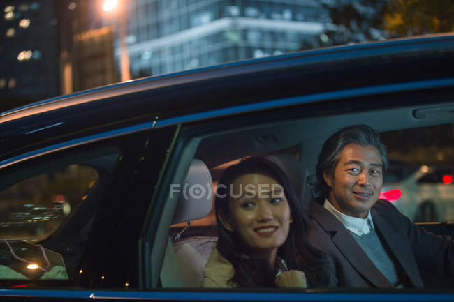 Feliz asiático casal equitação no carro e olhando para fora da janela à noite — Fotografia de Stock