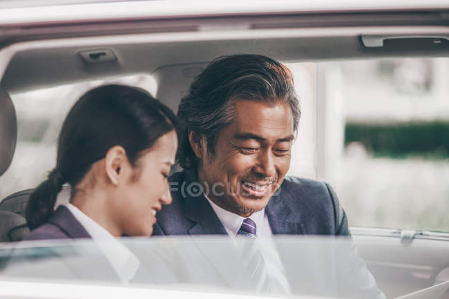 Smiling asian business people sitting in car — Stock Photo