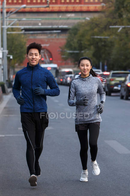 Вид спереду азіатського чоловіка і жінки в спортивному одязі, що бігає разом на вулиці — стокове фото