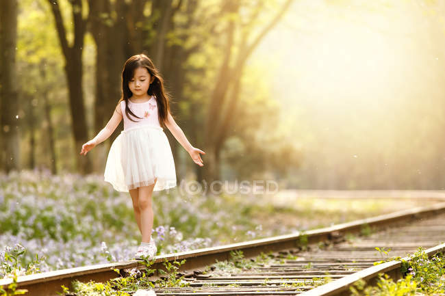 Adorable asiático niño caminar en ferrocarril en sunny tarde - foto de stock