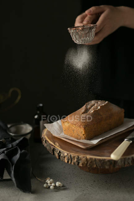 Recortado tiro de persona tamizar harina en pan fresco, proceso de fabricación de pan - foto de stock
