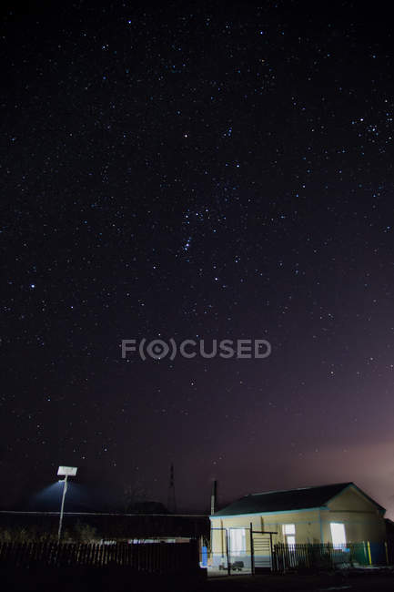 Majestic starry sky above illuminated house at night — Stock Photo