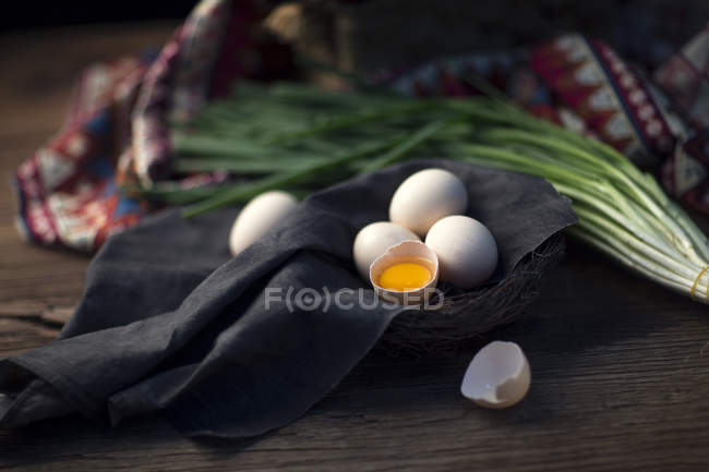 Close-up view of raw eggs and onion on wooden table — Stock Photo