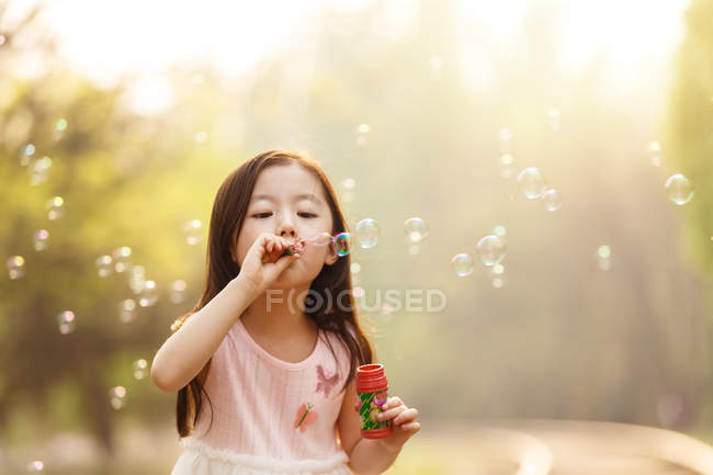 Entzückende asiatische Kind pustet Seifenblasen in der Nähe der Eisenbahn — Stockfoto