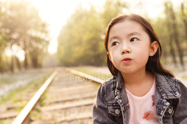 Retrato adorable asiático niño mueca cerca de ferrocarril - foto de stock