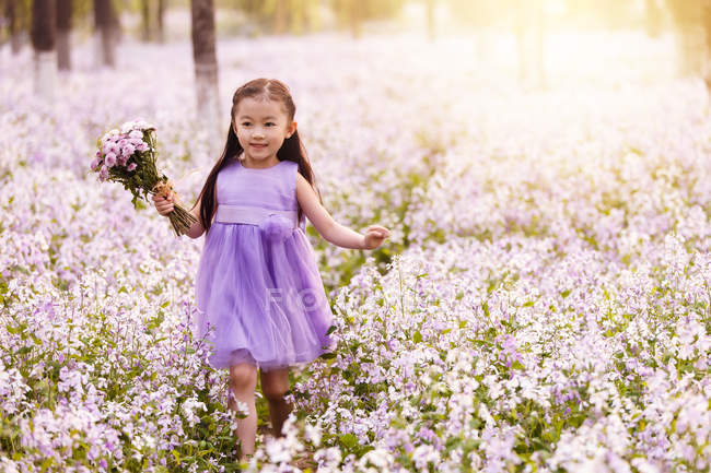 Adorável asiático criança no vestido andando com buquê de flores no campo — Fotografia de Stock