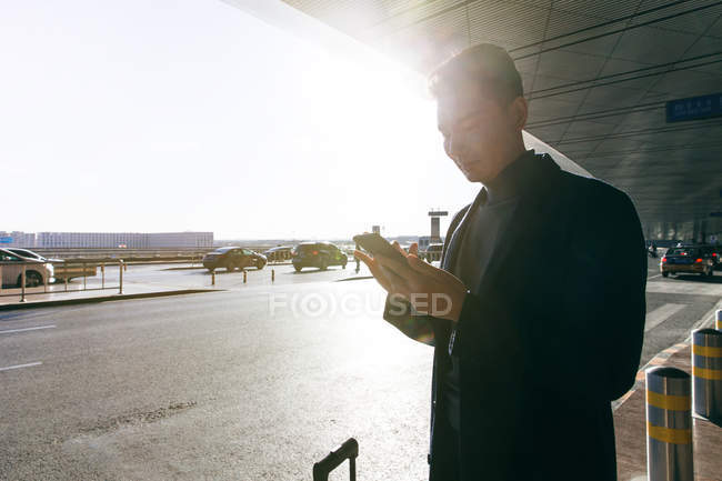 Молодой бизнесмен, использующий смартфон в аэропорту — стоковое фото
