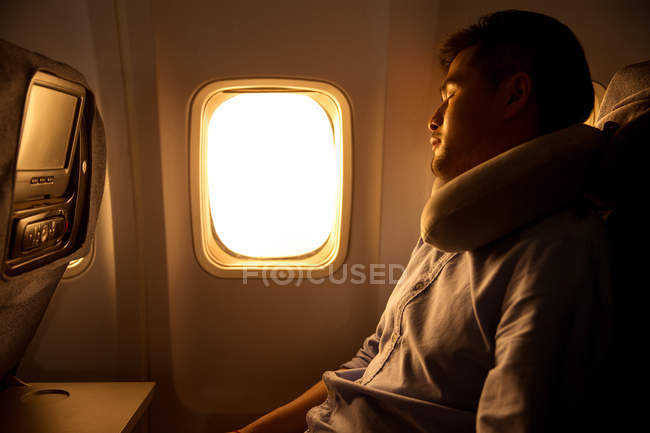 Joven durmiendo sentado en el avión - foto de stock